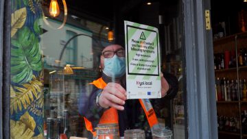 COVID Support Officer putting poster in shop window