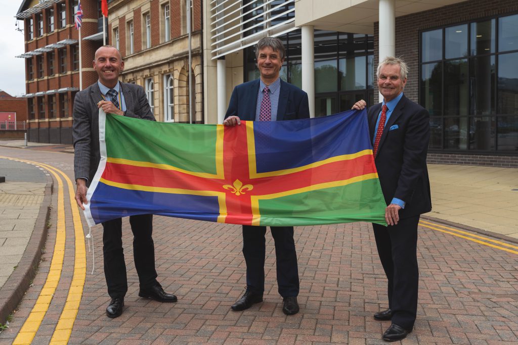 Leaders of Greater Lincolnshire, North Lincolnshire and North East Lincolnshire Councils holding a Lincolnshire flag