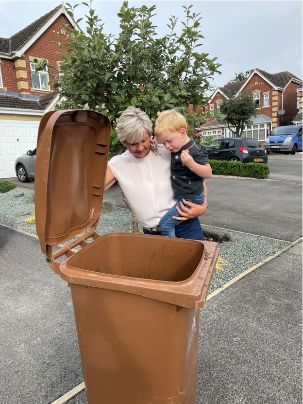 Mason with grandmother Jo checks the garden waste bin is empty