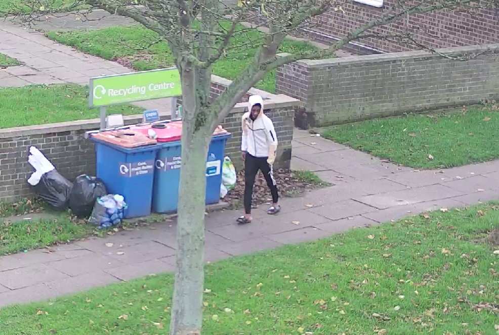 A person walking near some bins
