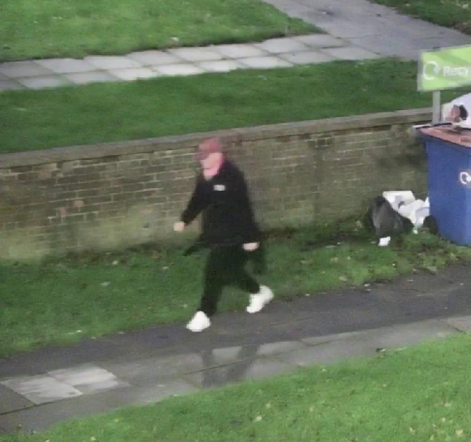 A person walking away from bins.