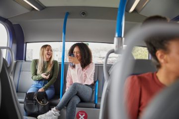 Two people sitting on a bus chatting.