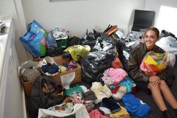 Izzy Greenard sits on the floor next to the donations for the pop up hospice event.