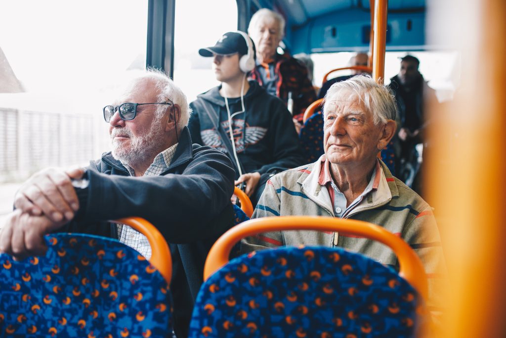 Two elderly people sitting on a bus.