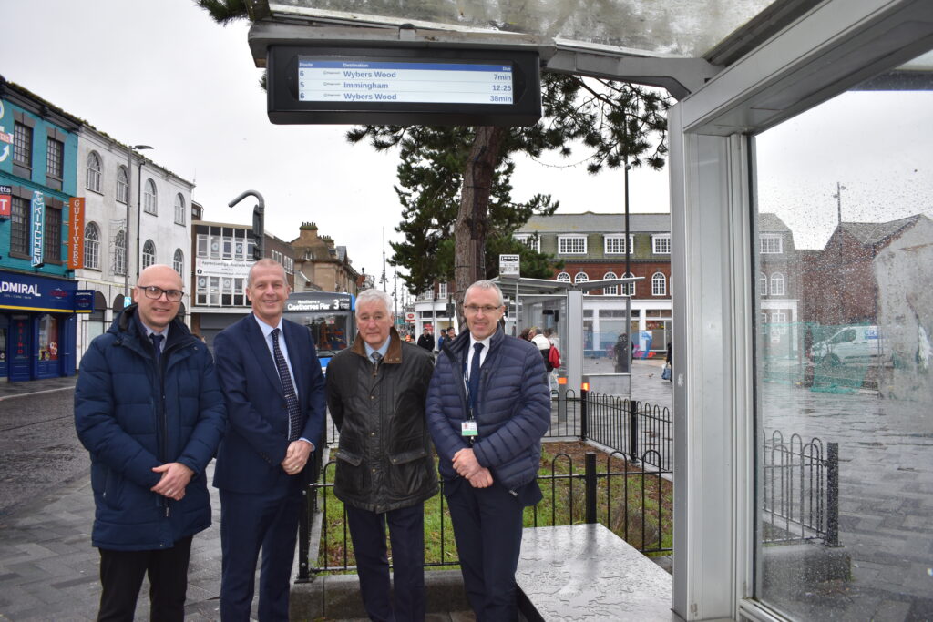 Four men standing in front of a bus stop.