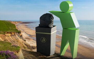 A large green stick figure putting Rubbish in a bin by the seaside