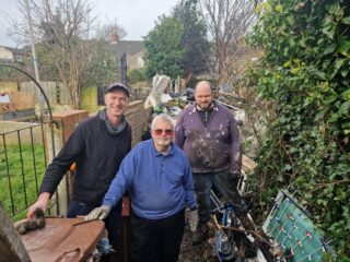 Three male local residents stood in front of a pile or rubbish down a private alleyway off Castle Street, Grimsby