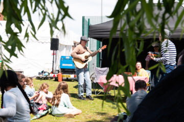 Person playing guitar in front of a small crowd