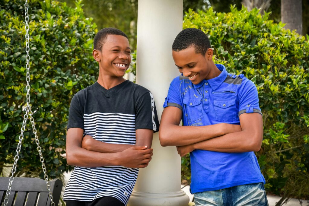 Two teenage boys smiling with their arms crossed