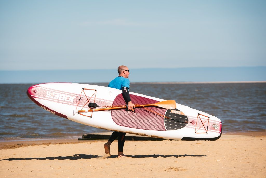 Man walking into the water with a paddleboard 