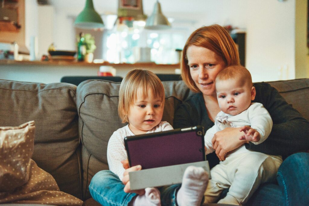Woman, child and baby sat looking at a digital tablet