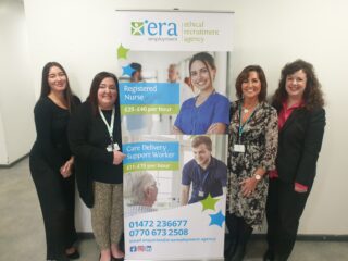 Four women with a pop up banner representing the Ethical Recruitment Agency