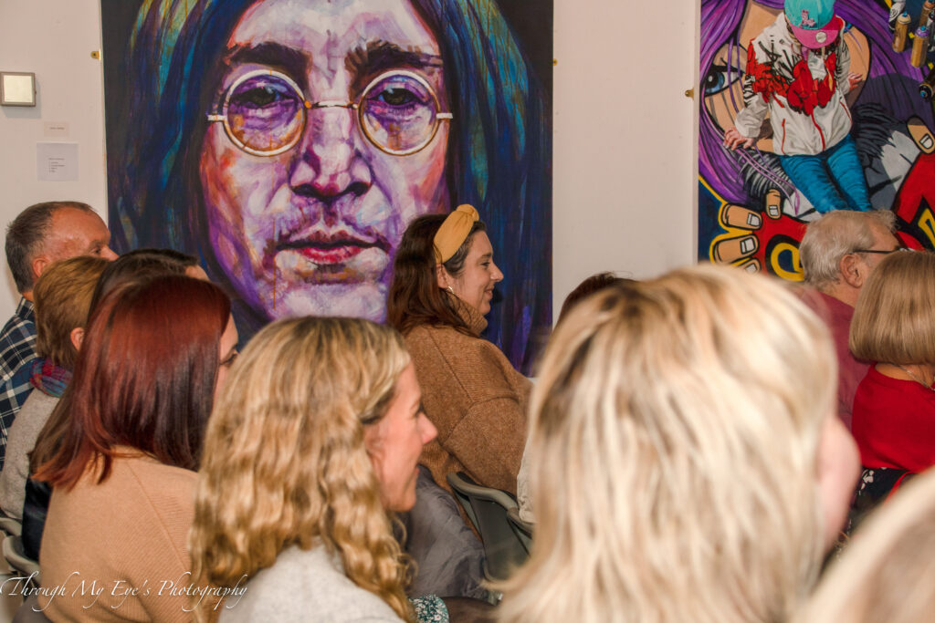 People sat listening to a talk in front of artwork at the Albert Room, Cleethorpes