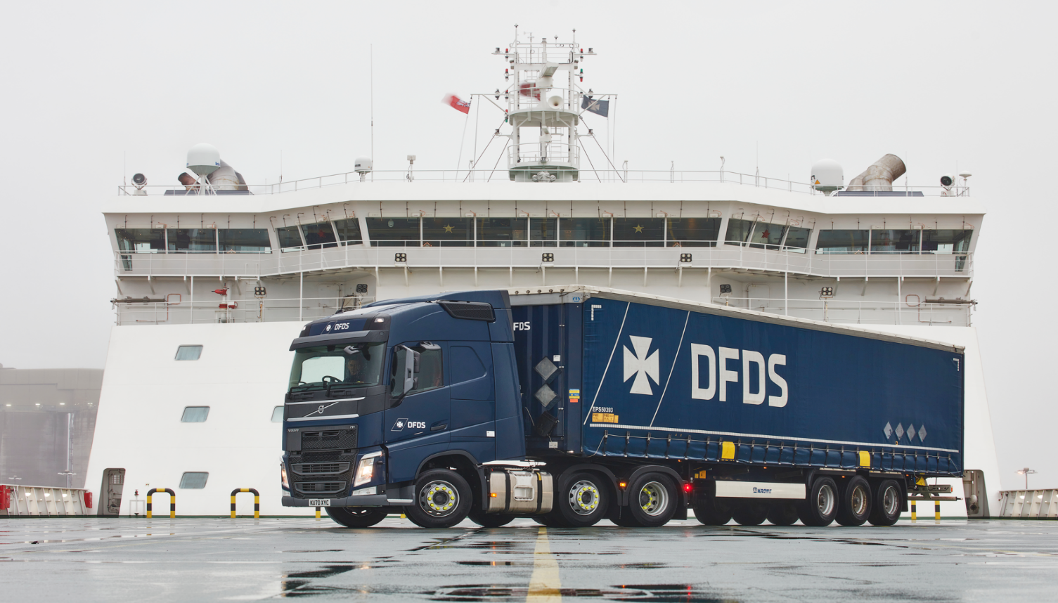 DFDS truck parked in front of a large ship in the port