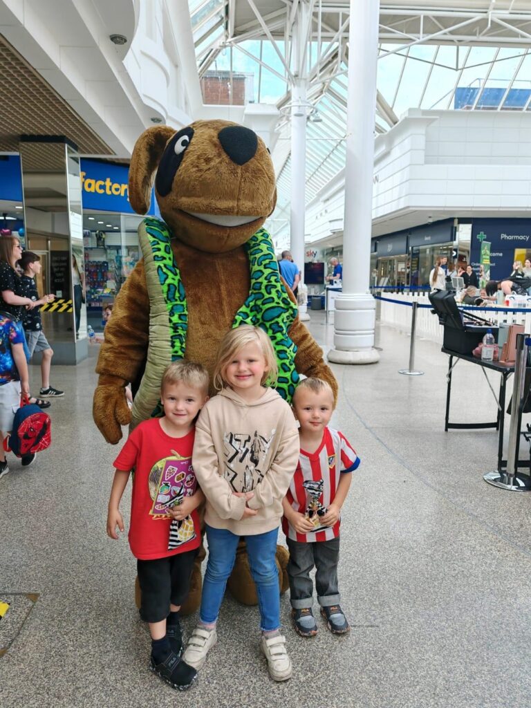 Three children in front of a dog mascot
