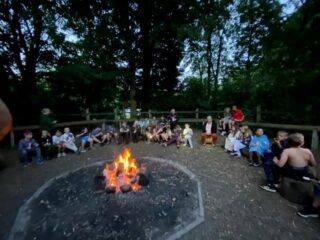 A photo of young carers sat around a camp fire