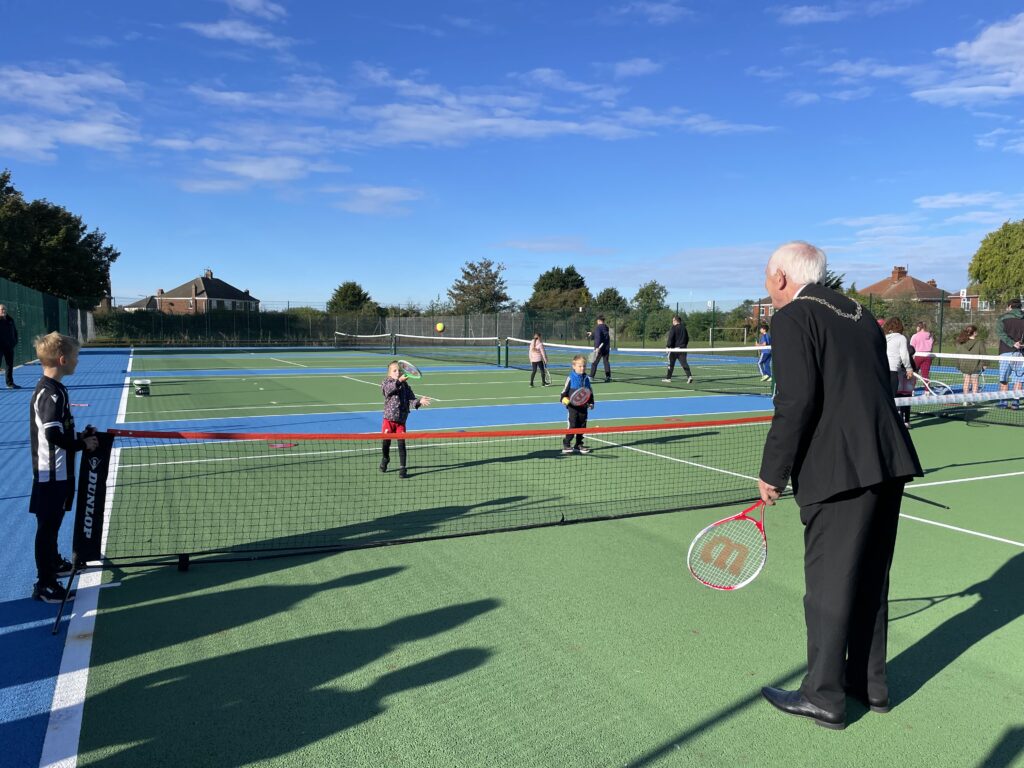 Children playing tennis with the Mayor at the opening day of the courts