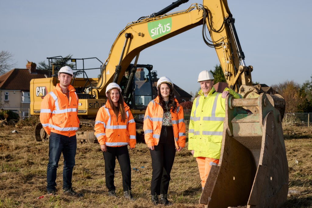 Western Housing site, four people stood in front of a CAT digger