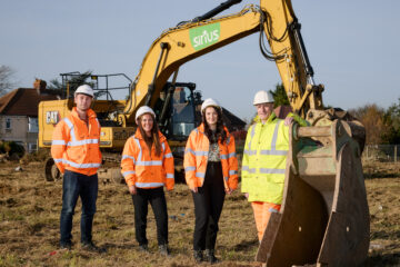 Western Housing site, four people stood in front of a CAT digger