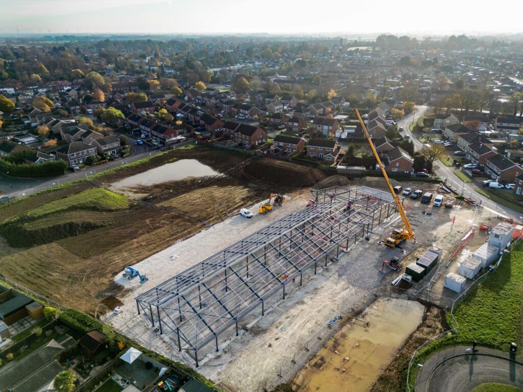 A steel frame being erected by a yellow crane