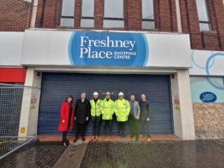 Several people in front of a Freshney Place sign