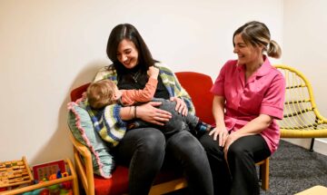Kathryn Hall breastfeeding her son with Zoe Hegarty, infant feeding supporter