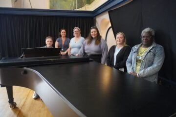 Children in care choir stood around a piano