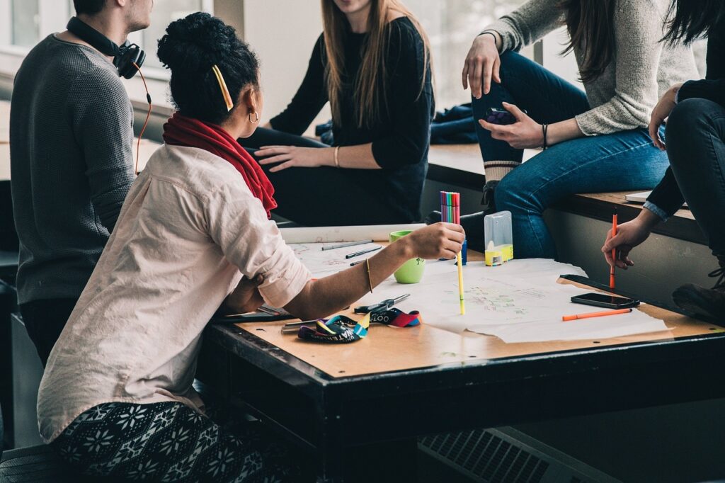 A group of young people sat around a table with pens and paper