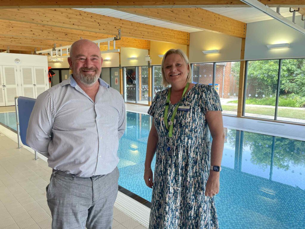 A photo of Humberston Park headteacher, and business manager, posing for a photo in front of the pool