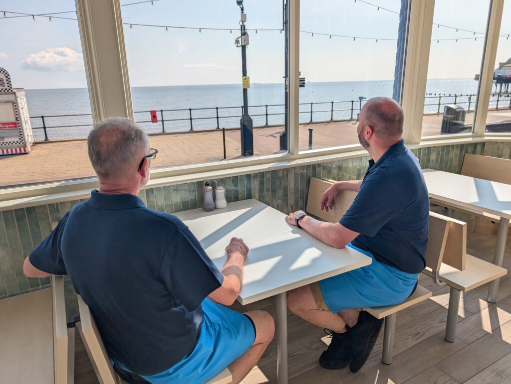 Two men looking out to sea from inside a building