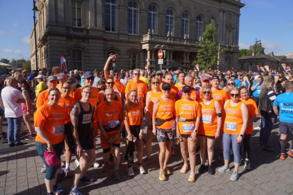 A group of people in bright orange t shirts ready for a run