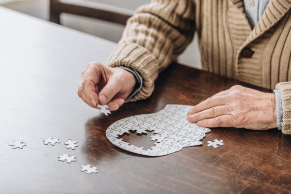 Male playing with jigsaw puzzle of head with missing pieces intended to depict struggling with mental health