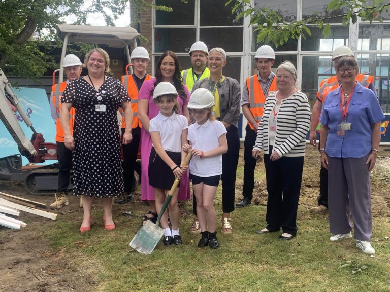 Two year five pupils dig a spade into the ground as others look on.