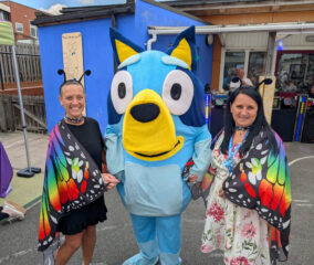 Bluey and 2 members of staff dressed up as butterflies at the Central Family Hub smiling