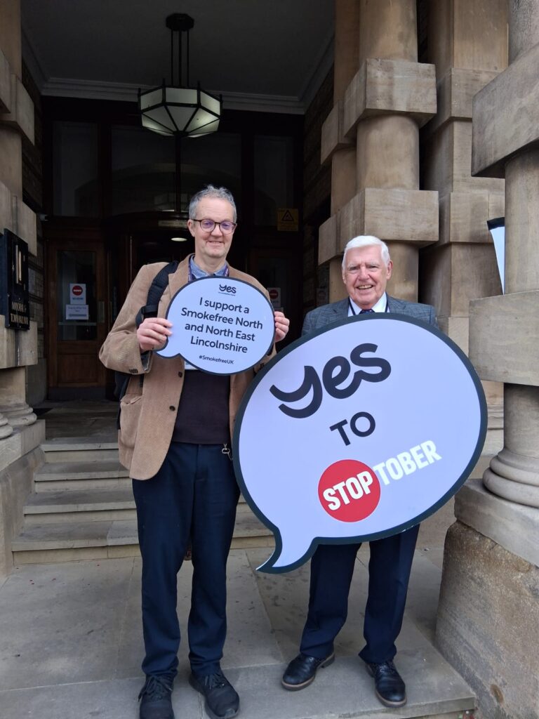Geoff Barnes and Cllr Shreeve support Stoptober with two signs in front of Grimsby Town Hall