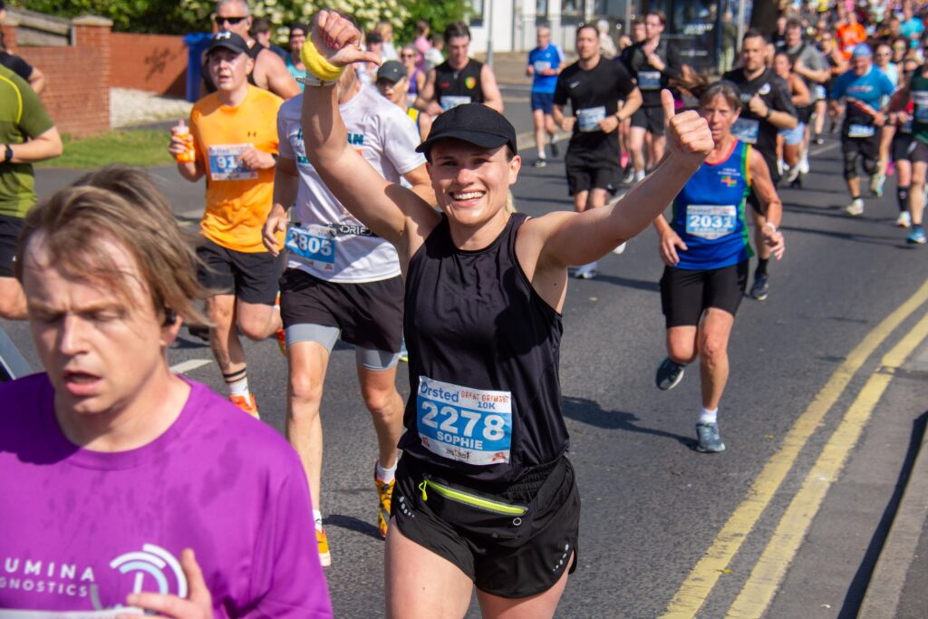 A runner waving to the camera in the 2025 Orsted Great Grimsby 10K.