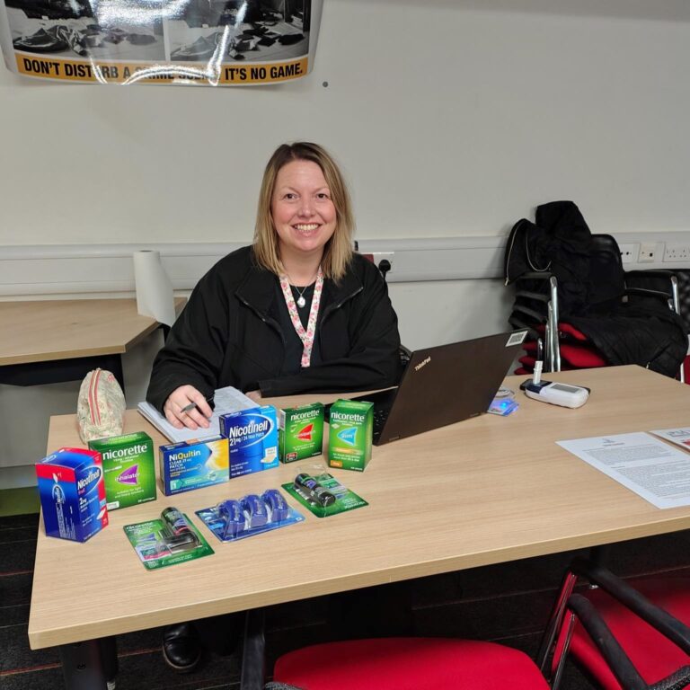 Maria sits at a table with stop smoking NRT products