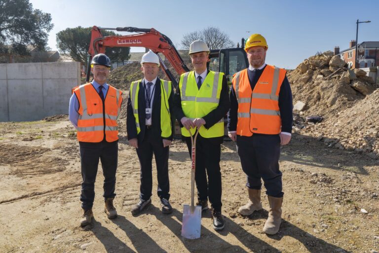 People in front of construction machinery at Sea Road site