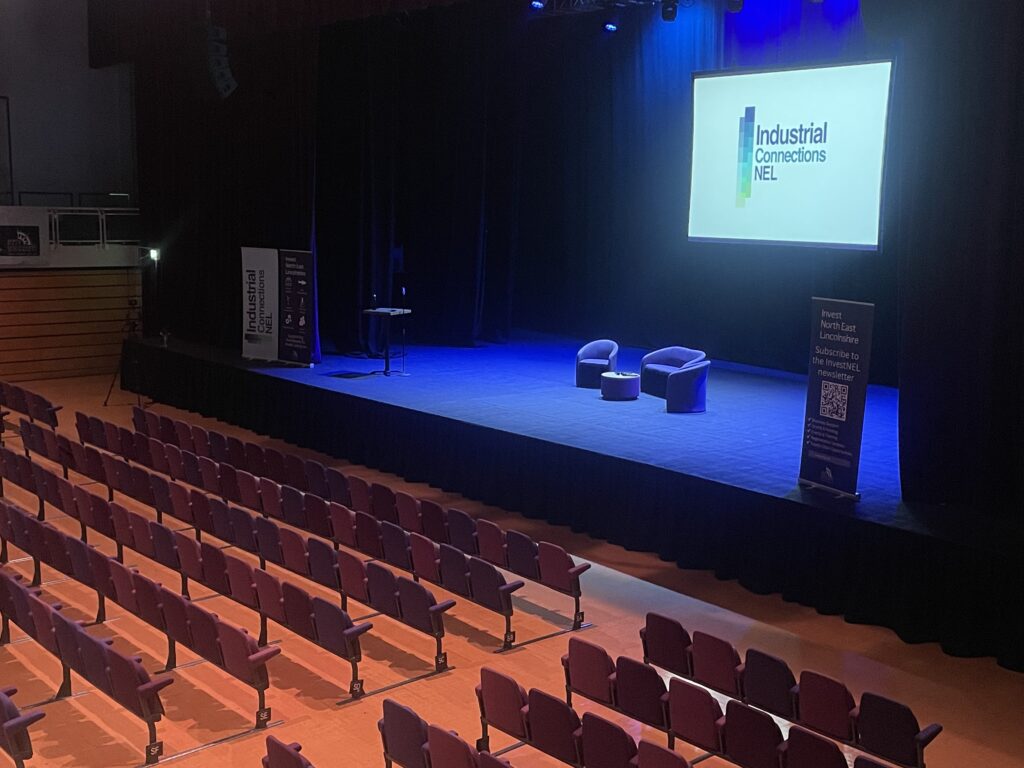 A photo of the Auditorium stage with chairs set out under a blue light