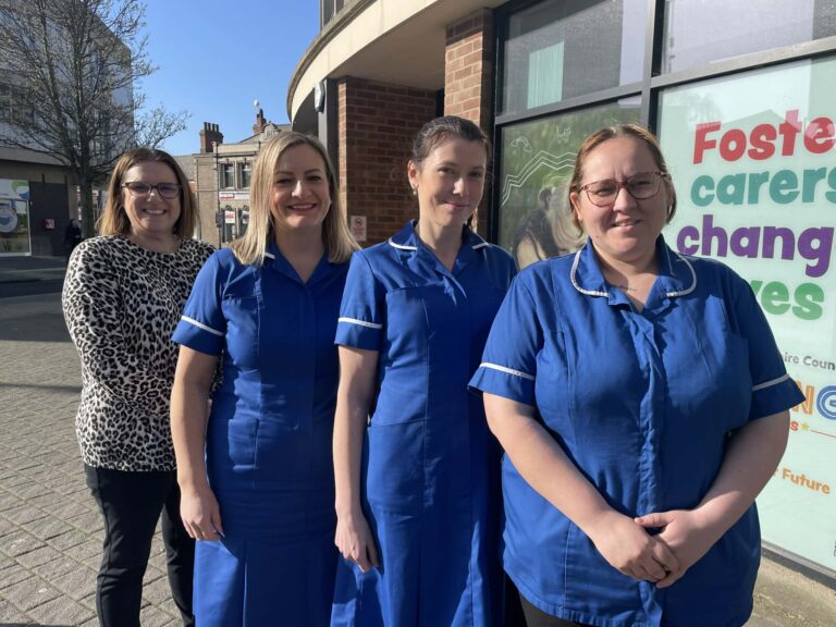 A photo of four health visitors posing outside a building in Grimsby Town Centre