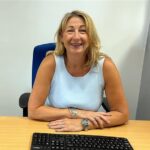Sharon Wroot sat at a desk smiling