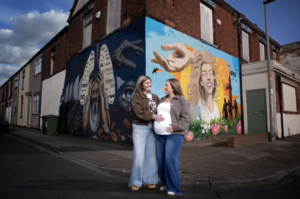 Wendy and her daughter Amy stand in front of the smoking mural on the corner of a Grimsby street
