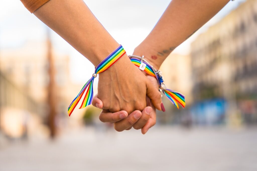 Two hands holding with a pride band on