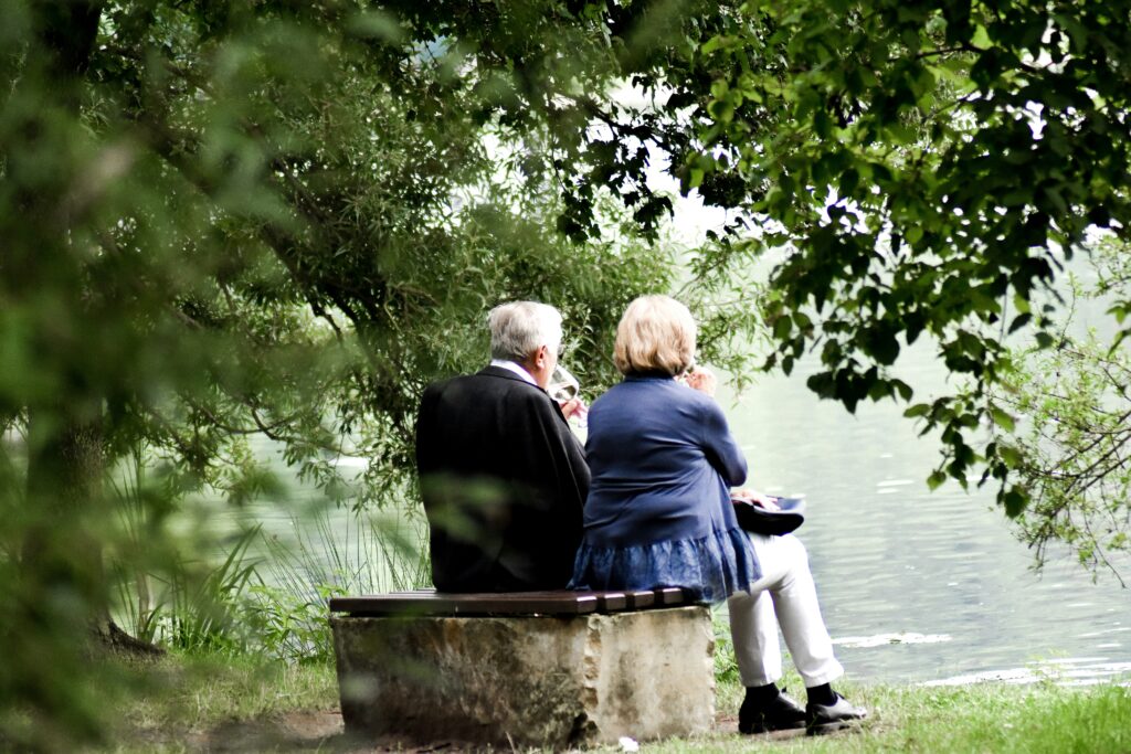 Two older people sat on a bench