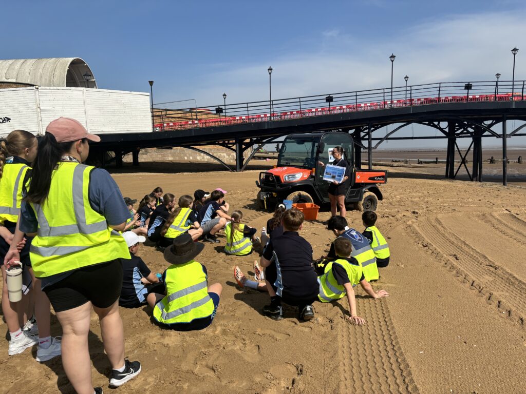 Children sat on the beach talking to resort hub