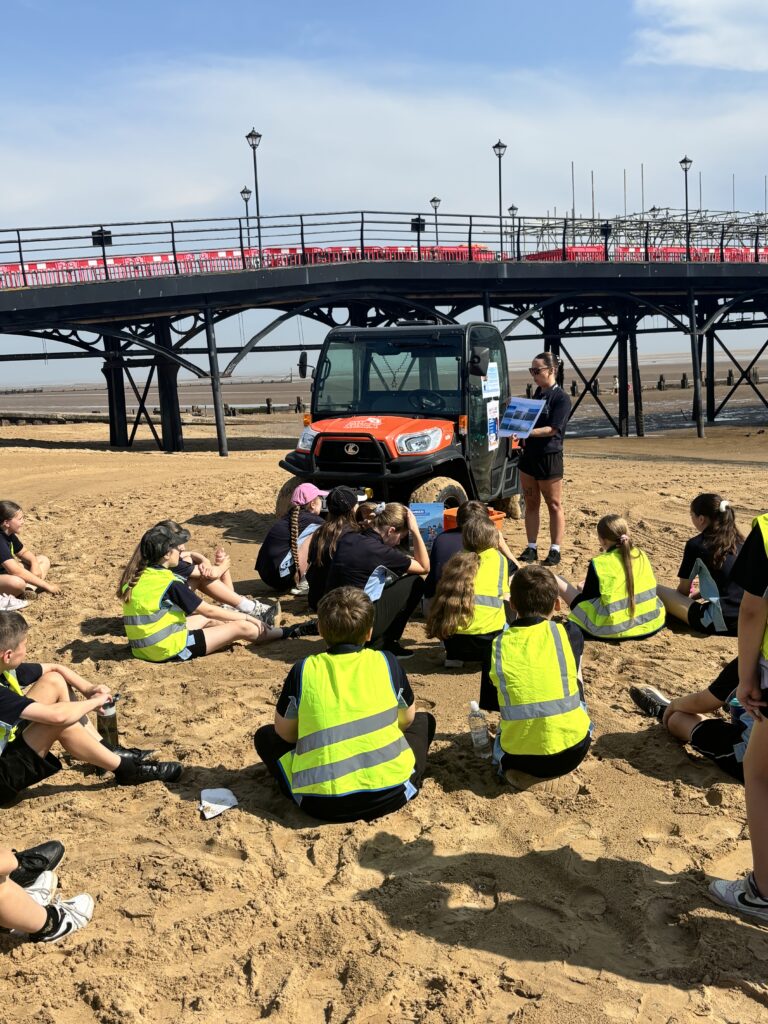 Children sat on the beach talking to resort hub