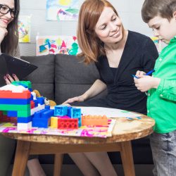 Child playing Child playing with blocks with two adults watching