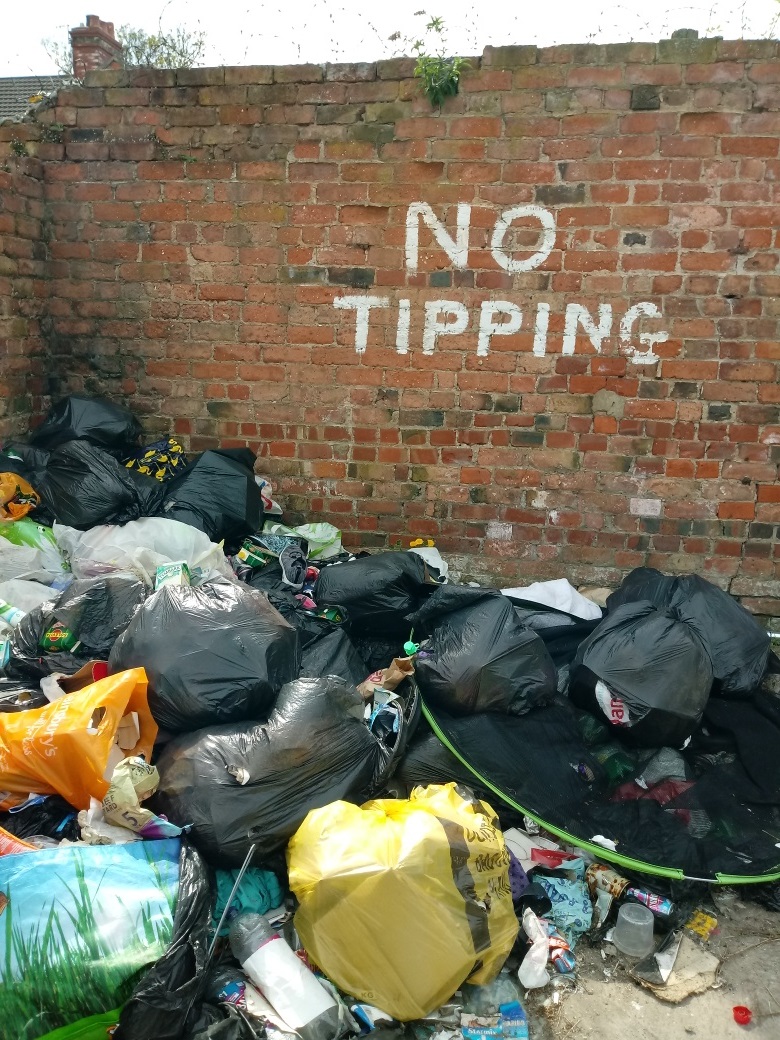 Bags of rubbish piled next to a wall.